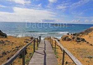 un sentiero in legno che conduce all'oceano su una spiaggia di Made in Salento - LU MARE a Torre San Giovanni Ugento