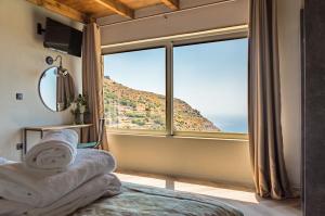 a bedroom with a large window with a mountain view at INO I, sea goddess domus by Amigdalokefali Elafonissi in Kissamos