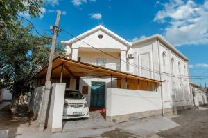 ein weißes Haus mit einem davor geparkt in der Unterkunft Xurshidabonu Guest House in Xiva