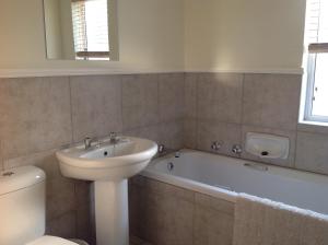 a bathroom with a sink and a toilet and a bath tub at Riverclub Villas in Plettenberg Bay +41 photos