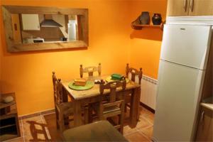 Casa Rural Fuente Tía Canora في Solosancho: مطبخ مع طاولة وثلاجة بيضاء