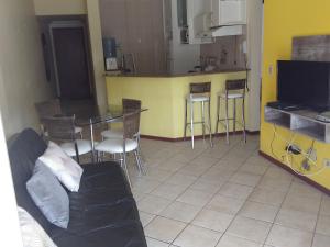 sala de estar con sofá, mesa y cocina en Vila das Gaivotas, en Florianópolis