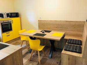 uma cozinha com uma mesa de madeira e cadeiras amarelas em Ferienwohnung Horn em Pirna