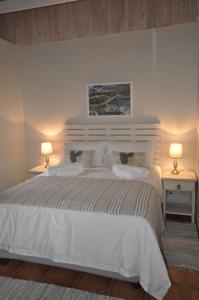 1 dormitorio con 1 cama blanca grande y 2 lámparas en The Loft on Lambert, en Port Alfred