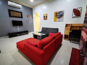 a living room with a red couch and a tv at Amera Homestay in Cukai