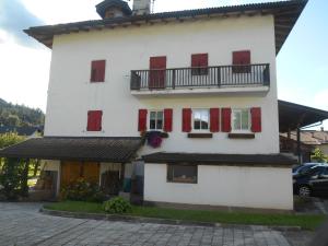 a white building with red shutters and a balcony at CASA CAMPAGNA in Cavalese