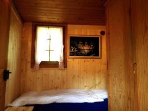 a bedroom with a bed in a wooden room with a window at Charmant Petit Chalet 3 étoiles en Gruyère in Crésuz