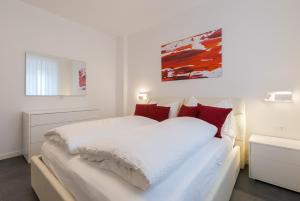 una camera bianca con un grande letto con cuscini rossi di Apartment Hanni a Merano