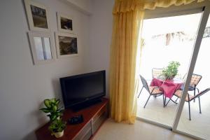 a living room with a flat screen tv and a table with a chair at Casa Lola in Agaete