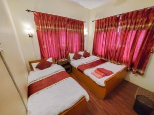 two beds in a small room with red curtains at Hotel Cordial in Pokhara