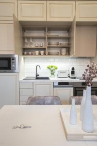 a kitchen with white cabinets and a table with vases at EL GUSTO HOMES Park in Sopron