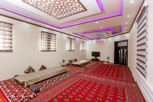 Habitación con alfombras rojas y techo con luces moradas. en Xurshidabonu Guest House, en Khiva