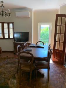 a dining room with a table and chairs and a television at Casa da Fonte in Seia