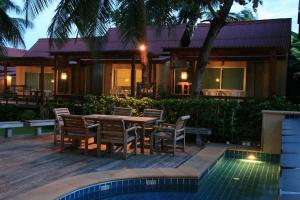 a house with a table and chairs next to a pool at Palita Lodge - SHA Plus in Haad Rin