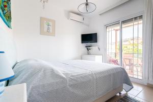 a white bedroom with a bed and a window at Anthos Apartments in Limenas