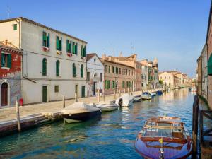 een groep boten aangemeerd in een kanaal met gebouwen bij ART PAINTING apartment with canal view in Venetië