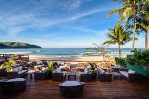 a beach with tables, chairs and umbrellas at Coconut's Maresias Hotel in Maresias