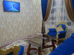 sala de estar con sillas azules y TV en la pared en Апартаменты Registan, en Samarkand