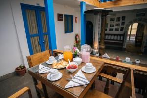 einem Holztisch mit Essen und Orangensaft darauf in der Unterkunft La Casa de Mayte in Cusco
