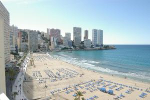 einen Strand mit Liegestühlen und Sonnenschirmen und dem Meer in der Unterkunft Apartamentos Carolina - Arca Rent in Benidorm