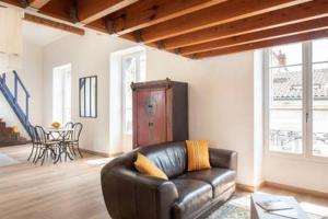 a living room with a leather couch and a table at beau meublé centre historique in Bordeaux