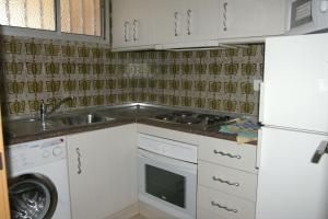 a kitchen with a sink and a stove and a refrigerator at Apartamentos Carolina - Arca Rent in Benidorm