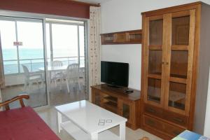 ein Wohnzimmer mit einem TV und ein Wohnzimmer mit einem Tisch in der Unterkunft Apartamentos Carolina - Arca Rent in Benidorm