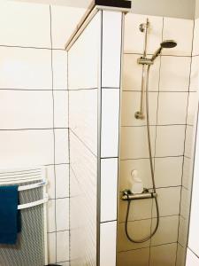 a shower in a bathroom with white tiles at Maisonnette vue sur la montagne in Vagney