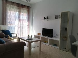 uma sala de estar com um sofá, uma televisão e uma mesa em Chalk house em Tarifa