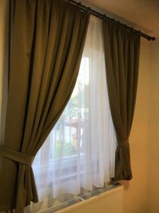 una ventana con cortinas verdes y blancas en Toscan Panzió, en Gyál