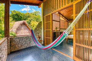 a hammock on the porch of a house at Omega Tours Eco-Jungle Lodge in La Ceiba