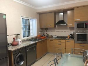 a kitchen with wooden cabinets and a sink and a dishwasher at Beachouse Algarve in Manta Rota