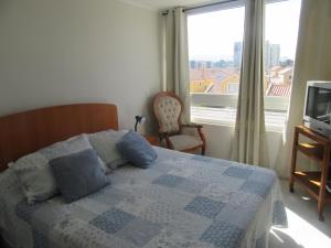 a bedroom with a bed with blue pillows and a window at Aparthotel Serena in La Serena