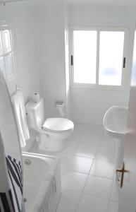 Baño blanco con aseo y lavamanos en Hotel Abrego Reinosa, en Reinosa