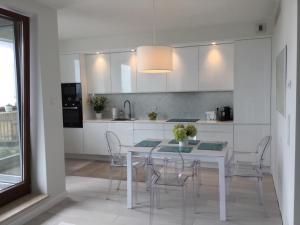 a white kitchen with a white table and chairs at Apartament Sea Towers View in Gdynia