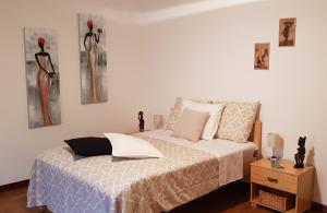 a bedroom with a bed and two dresses on the wall at Suites "Villa Alegria", Tarrafal in Tarrafal