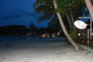 a beach at night with palm trees and a sign at Palita Lodge - SHA Plus in Haad Rin