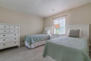 a bedroom with two beds and a dresser and a window at Buttonwood Cottage in Siesta Key