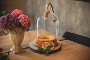 a glass dome on a table with a cake and a vase with flowers at Casal dos Capelinhos - Douro in Santa Marta de Penagui&atilde;o