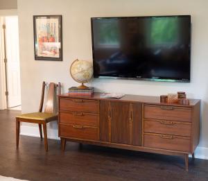 a large flat screen tv sitting on top of a wooden dresser at The Henry Carriage House in Bentonville