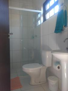 Baño blanco con aseo y lavamanos en Sun Suítes, en Ubatuba