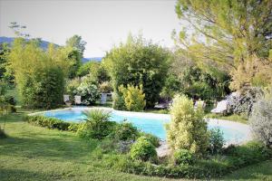une piscine dans un jardin avec des arbres et des buissons dans l'établissement Gites le Pimayon, à Manosque