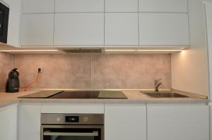 a kitchen with white cabinets and a sink at 52 Luxury Pool - AC/WIFI in La Mata
