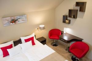 a bedroom with a bed and a desk and red chairs at MeDoRa Park - Hotel MeDoRa*** in Gárdony