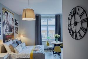 1 dormitorio con 1 cama y reloj en la pared en FLORIANSKA 32 by PI Apartments, en Cracovia