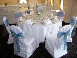 una mesa con manteles y sillas blancas en una habitación en The Treebridge Hotel, en Nunthorpe