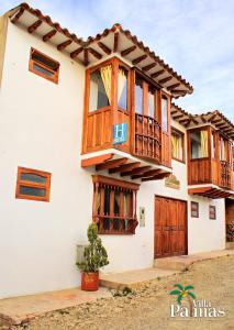 una casa con balcones de madera encima en Hotel Villa Palmas, en Villa de Leyva
