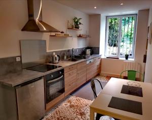 a kitchen with stainless steel appliances and a table at À tire-larigot in Cousances-aux-Forges