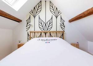 a bedroom with a white bed with a wall at La Chambre du 20 in Osthoffen