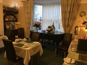 a dining room with a table and chairs and a table with flowers at Cornubia Guest House in Weymouth